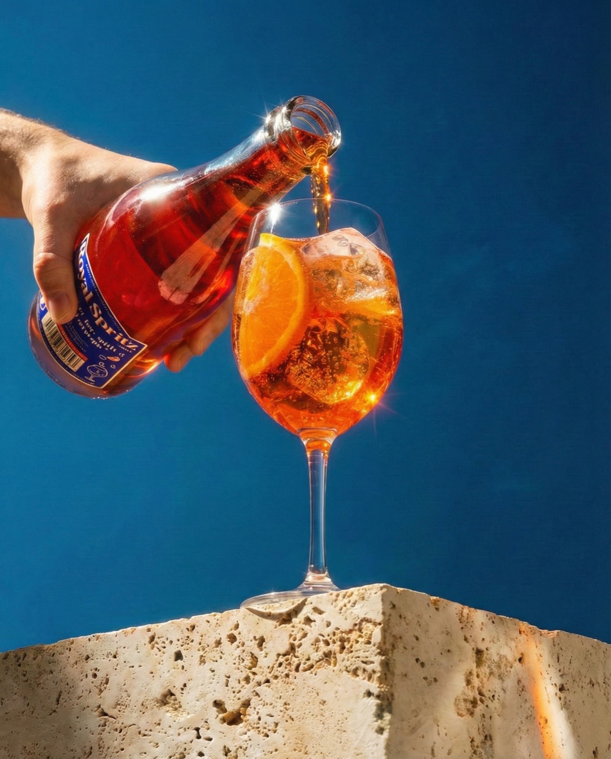 Royal Spritz wordt in een glas met ijs en sinaasappel geschonken